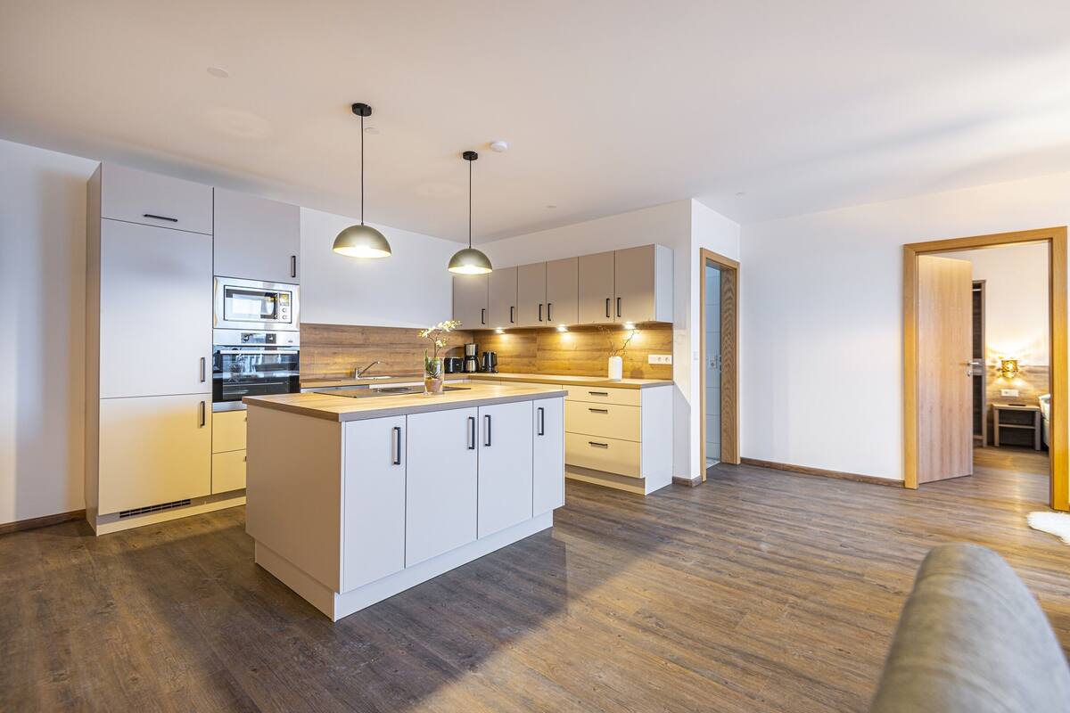 A modern kitchen with white cabinetry, a central island, and pendant lighting.