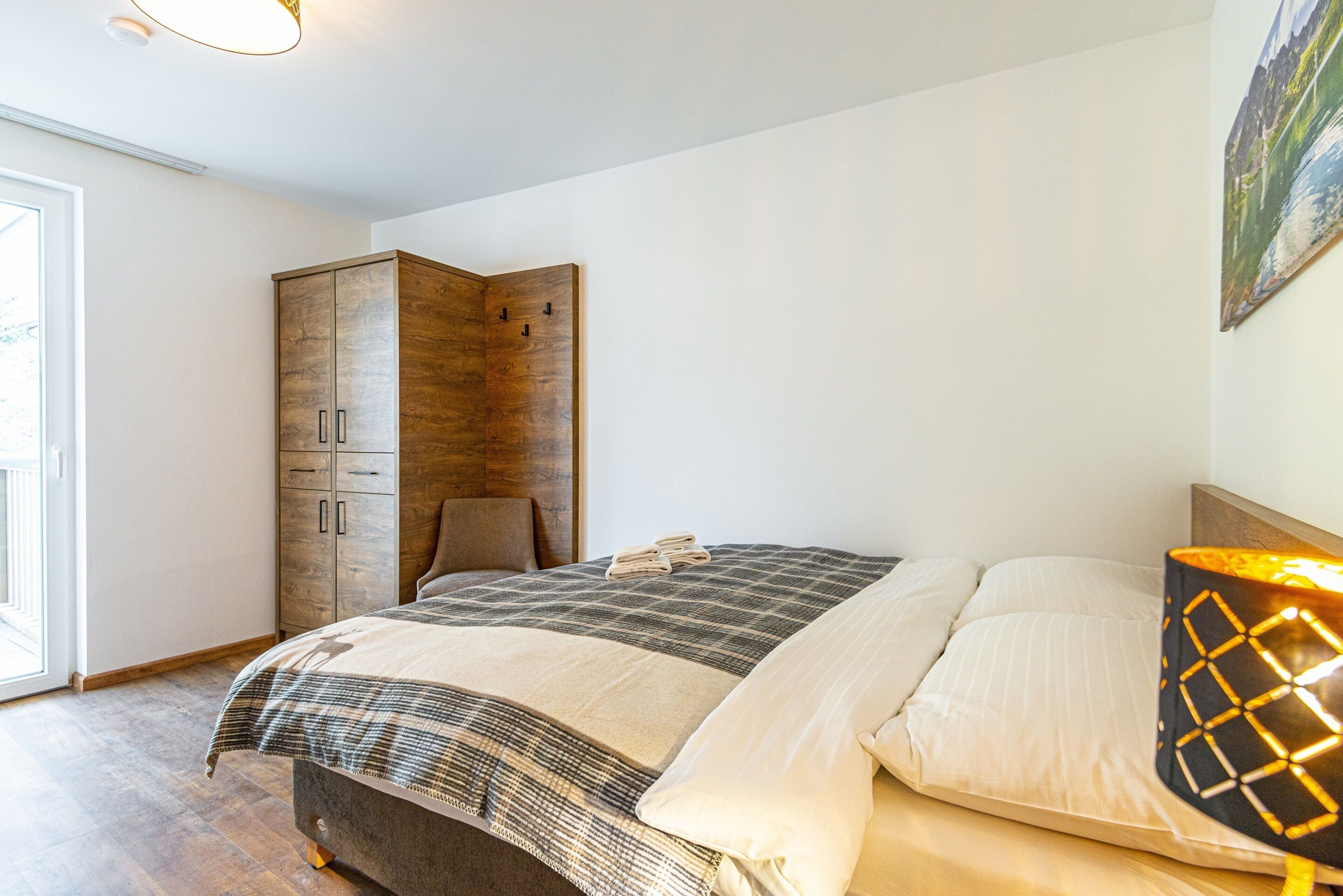 A bedroom with a bed, a wardrobe, and a lamp.