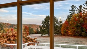 A view from a window with a white railing, overlooking a lake surrounded by autumn-colored trees and a hilly landscape. - Wonderful Views and Mountain Charm and on Beautiful 50 Acre Farm (Thornton)