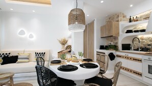 Een moderne keuken met witte kasten, een eettafel met zwarte borden en een hangende geweven lamp.