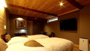 Habitación con dos camas, televisión, calefacción y una pequeña mesa con una silla.
