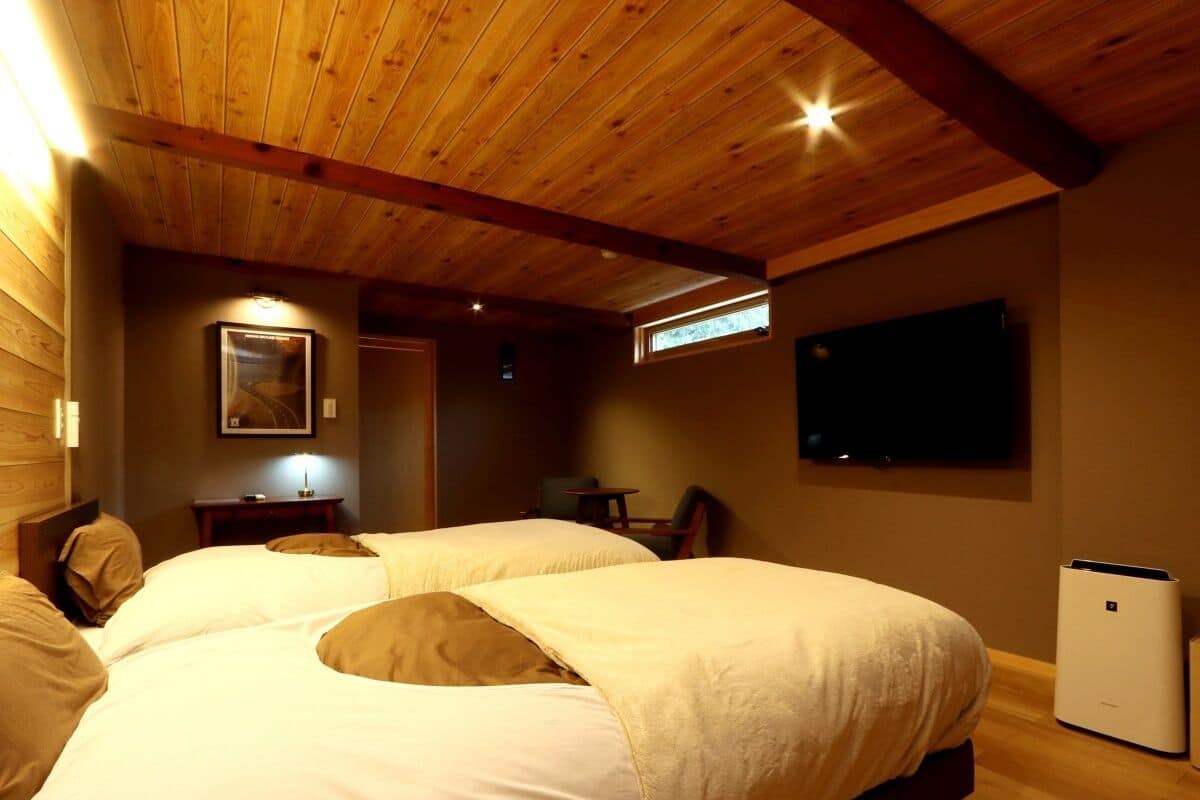 Quarto com duas camas, televisão, aquecedor e uma pequena mesa com cadeira.