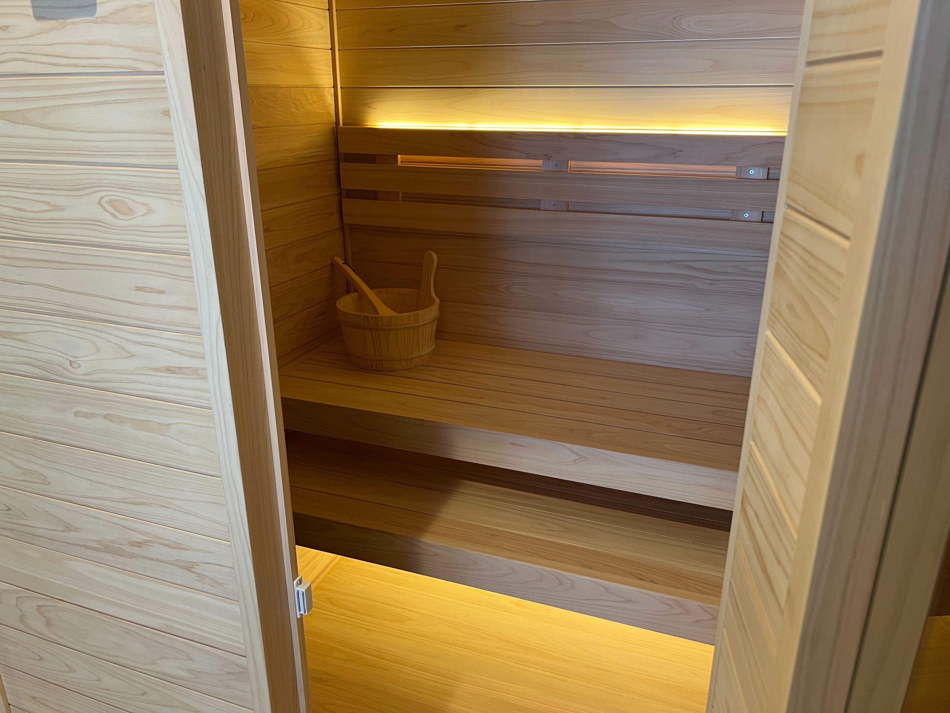 Eine Holzsauna mit einem Holzeimer und einer Holzbank.
