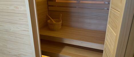 A wooden sauna with a wooden bucket and a wooden bench.