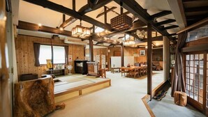 Un interior tradicional japonés con suelo de tatami, vigas de madera y techo bajo.