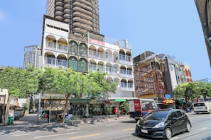 Un immeuble à plusieurs étages, avec un rez-de-chaussée à usage commercial, une enseigne bien visible et une structure imposante en arrière-plan.