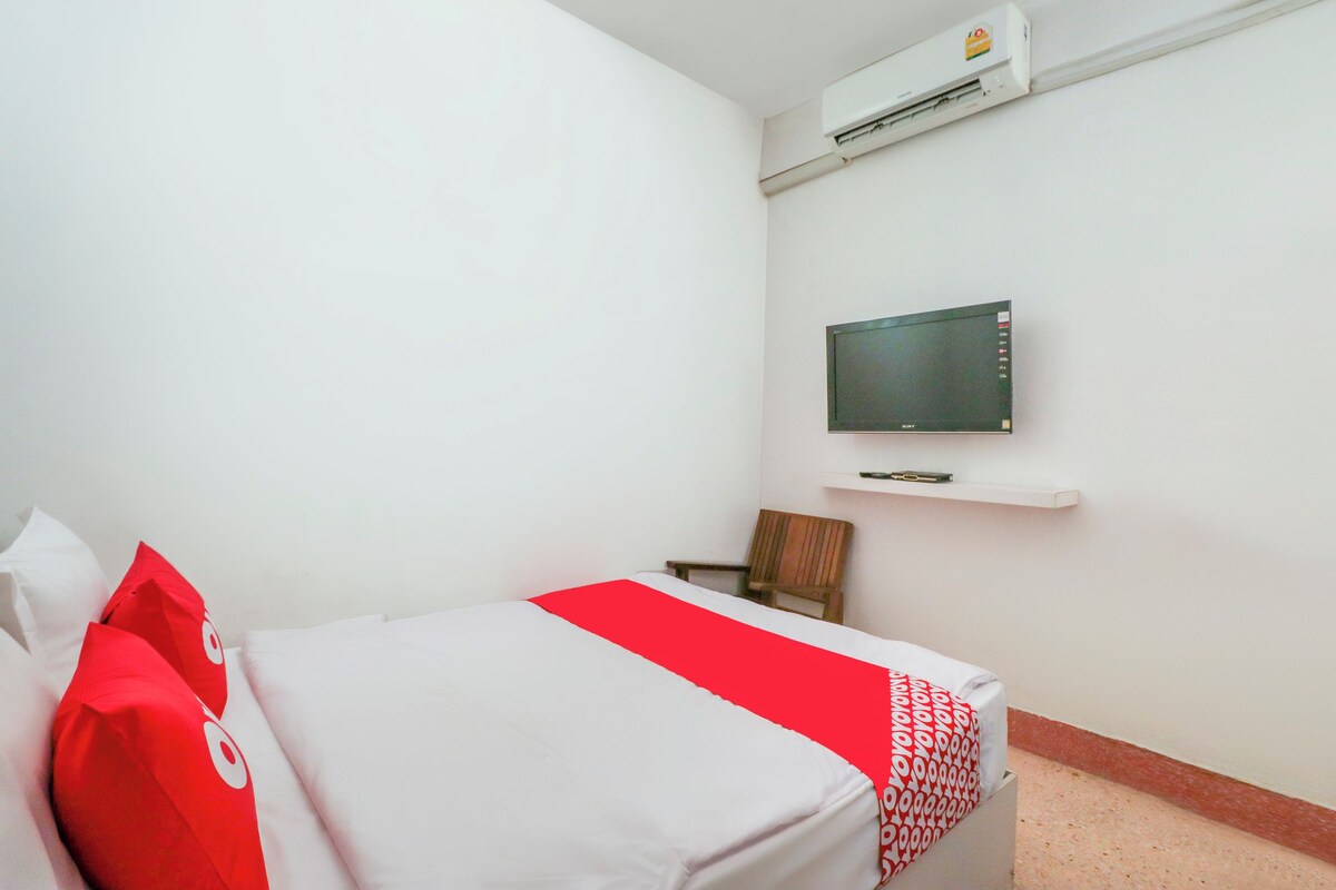 A hotel room with a bed, a TV mounted on the wall, and a chair.
