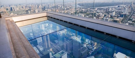 Un edificio alto con una piscina de fondo de cristal con vistas a un paisaje urbano.