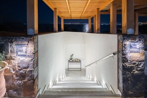 A staircase leading to a covered area with a view of a cityscape at night.