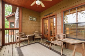 A wooden deck with a ceiling fan, wooden chairs, and a table. - Unwind and Relax! Walk-in Log Cabin with Gas Fireplace and Screened Balcony (Branson)