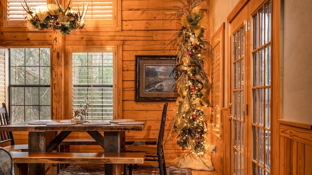 A wooden interior with a dining table, benches, and a decorated Christmas tree. - Unwind and Relax! Walk-in Log Cabin with Gas Fireplace and Screened Balcony (Branson)