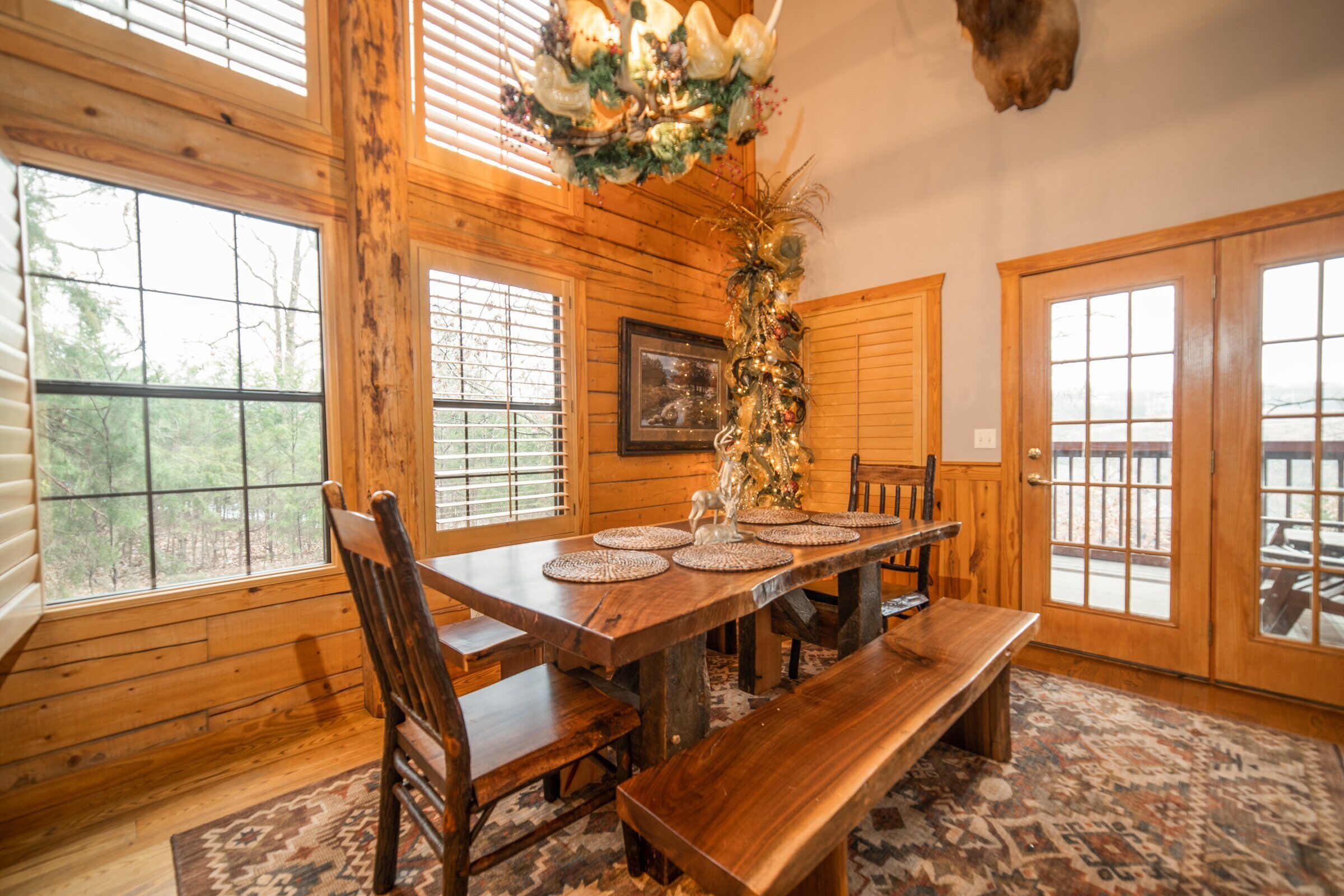 Une salle à manger en bois avec une grande table, des bancs et un élément décoratif central.
