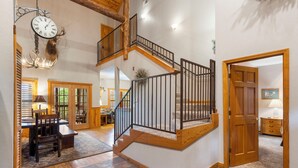 A spacious interior with a wooden staircase, a dining area, and a large chandelier. - Unwind and Relax! Walk-in Log Cabin with Gas Fireplace and Screened Balcony (Branson)