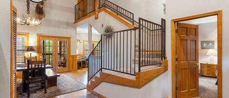 A spacious interior with a wooden staircase, a dining area, and a large chandelier.