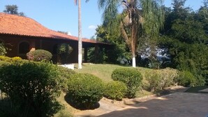 A building with a red-tiled roof, surrounded by well-maintained bushes and palm trees. - WONDERFUL HOME - FAMILY LEISURE (Itu)