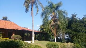 A building with a red-tiled roof, surrounded by well-maintained bushes and palm trees.