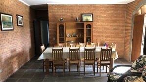 A dining area with a brick wall, a wooden table, and chairs. There is a television on a shelf above the table. - WONDERFUL HOME - FAMILY LEISURE (Itu)