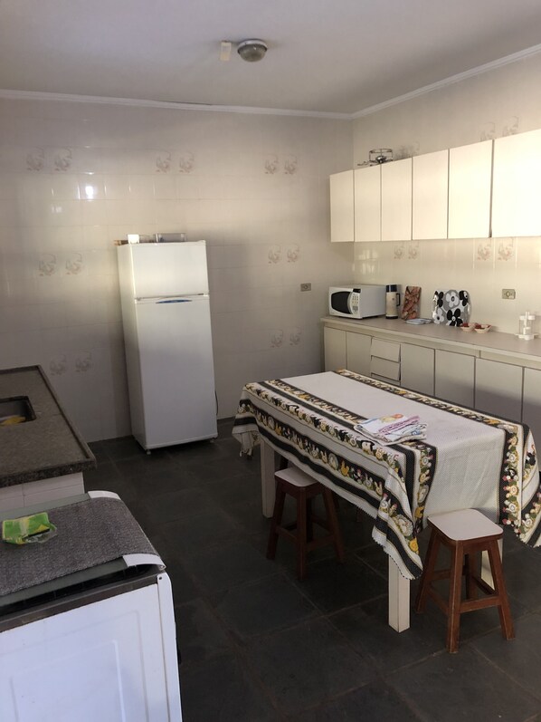 Compact kitchen with a refrigerator, microwave, and table for dining.