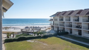 Un hôtel en bord de mer doté de nombreux balcons, d’une plage de sable et offrant une vue dégagée sur l’océan.