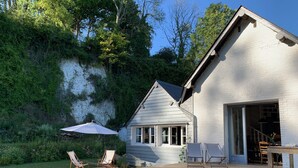 A white house with a deck, outdoor seating, and a staircase leading to the entrance.