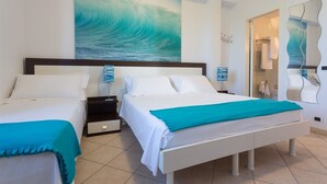 Een hotelkamer met twee bedden, een groot schilderij van een golf en een badkamer door een open deur zichtbaar.