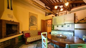 Un saló acollidor amb una xemeneia, un sofà i una taula de dinar amb caires.