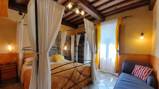 Quarto com cama, sofá e parede de pedra.