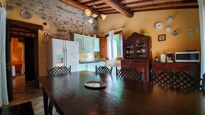 Uma cozinha rústica com mesa de madeira, paredes de pedra e decoração tradicional.