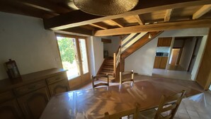 A spacious kitchen with a large island, wooden cabinets, and a staircase leading to an upper level.