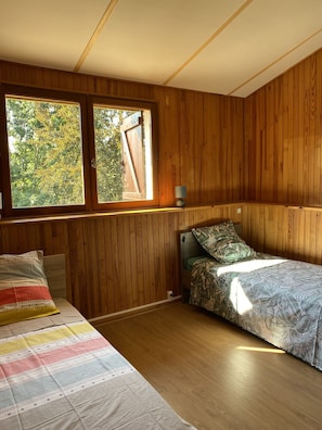 Een kamer met houten lambrisering, een bed, een bankje en een raam.