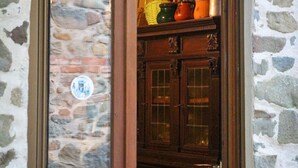 Un muro in pietra con una porta in legno che dà su una zona cucina con armadietti e un cesto appeso.