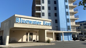 Un hôtel à plusieurs étages, appelé Bluewater East, avec une enseigne bien visible, un parking et un ciel d’un bleu éclatant.