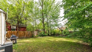 Un jardin avec une clôture en bois, un barbecue et une pelouse.