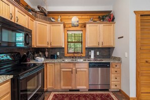 A kitchen with wooden cabinets, a stainless steel dishwasher, a built-in oven, and a granite countertop.