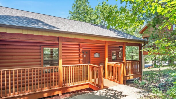A log cabin with a porch and a small deck, surrounded by trees and a clear sky. - 2 Queen BR Cozy Walk-in Log Cabin close to Branson Entertainment (Branson)