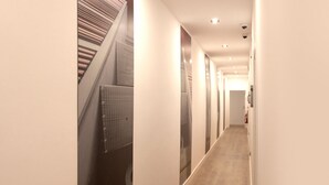A narrow, well-lit hallway with a staircase on the left and a fire extinguisher on the right. - Woohoo Rooms Fuencarral (Madrid)