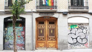 A building facade with a wooden door, a window with a colorful flag, and a wall with graffiti. - Woohoo Rooms Fuencarral (Madrid)