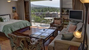 Una habitació d'hotel amb un balcó, un llit, un sofà, una taula de cafè i una televisió.