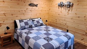 A wooden cabin room with a bed, a nightstand, and wall-mounted hooks. - "TWO MUCH FUN"   (De Queen)