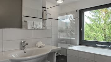 A modern bathroom with a large sink, mirror, and a shower area.