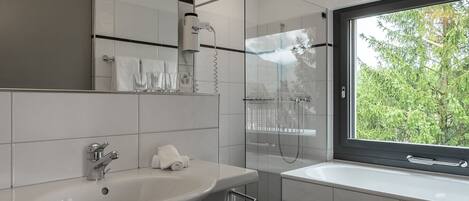 Un baño moderno con un lavamanos amplio, un espejo y una zona de ducha.