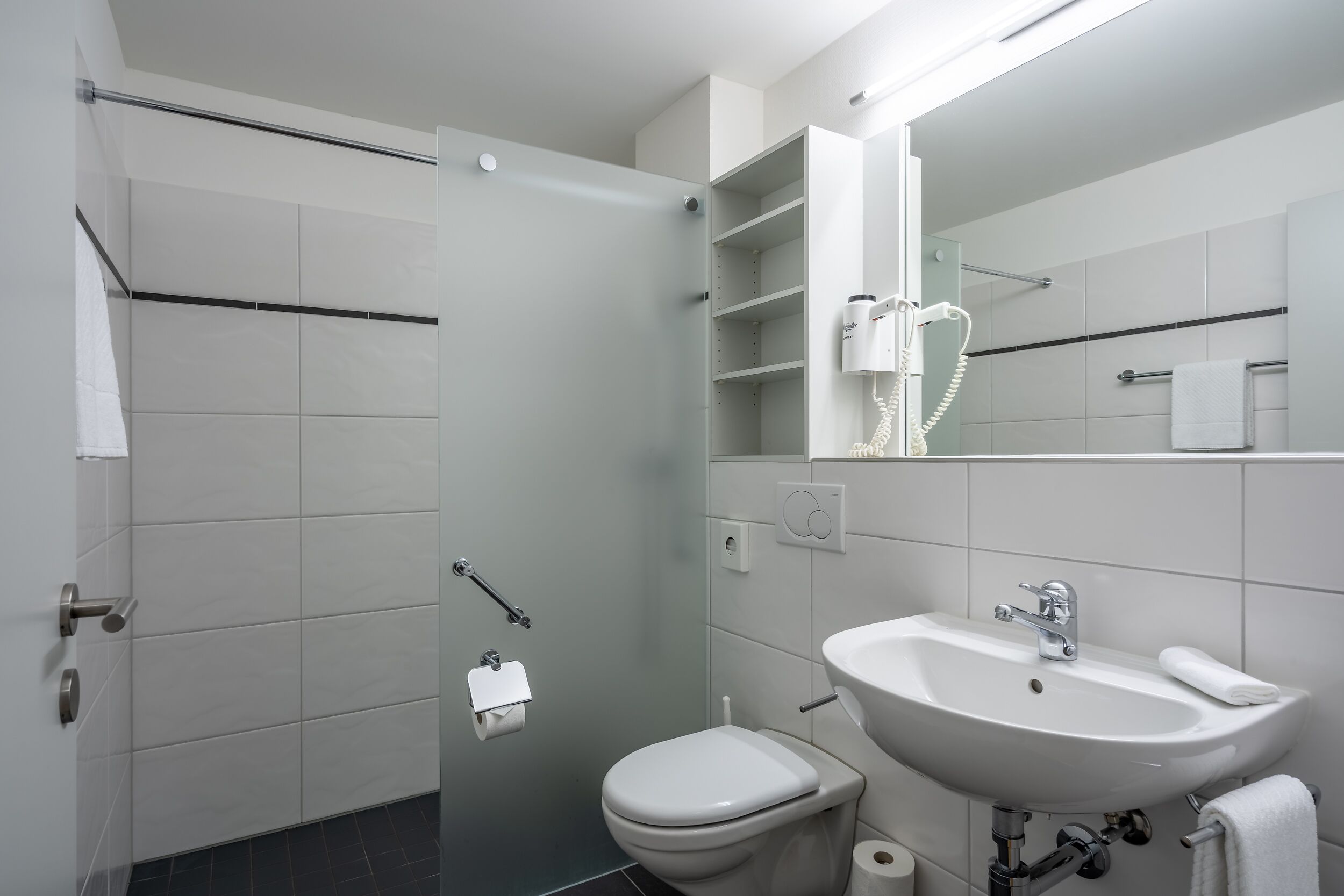 Ein modernes Badezimmer mit Toilette, Waschbecken und Dusche.