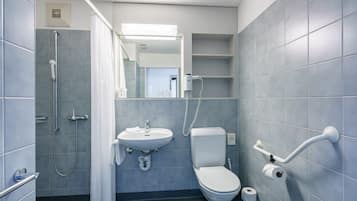 Baño con ducha, lavamanos, inodoro y barras de apoyo.