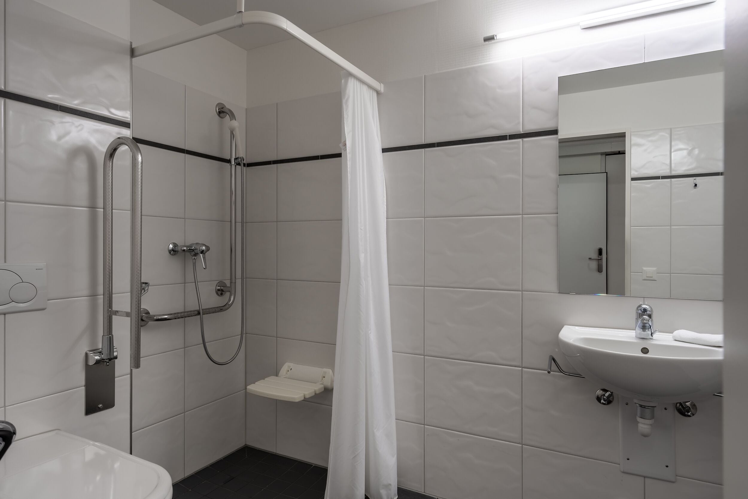 A modern bathroom with a shower, a sink, and a mirror.
