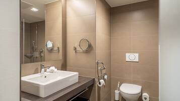 Un bagno moderno con un lavandino capiente, uno specchio, una doccia e un water.