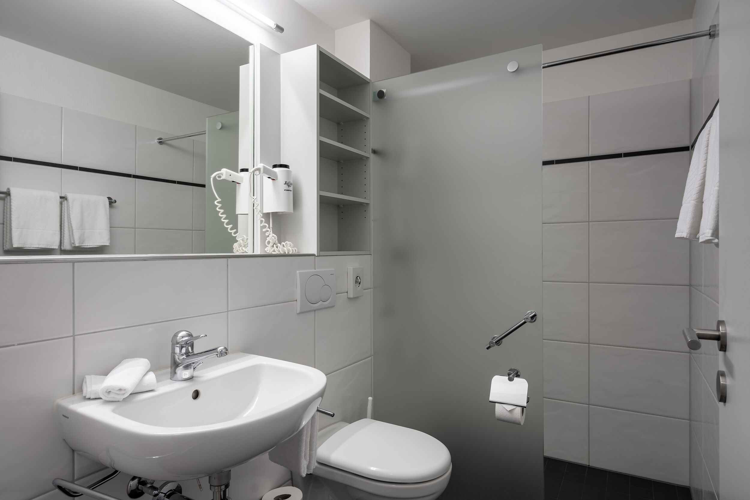 A modern bathroom with a white sink, toilet, and shower.