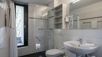 A modern bathroom with a glass-enclosed shower, a white sink, and a toilet.