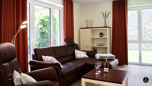Ein modernes Wohnzimmer mit einem braunen Ledersofa, einem Couchtisch mit Gläsern und einem Bücherregal.