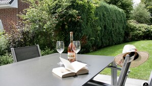 Ein Tisch im Freien mit einer Flasche, Gläsern und einem Buch.