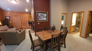 A cozy living room with a wooden dining table, wicker sofa, and a fireplace.